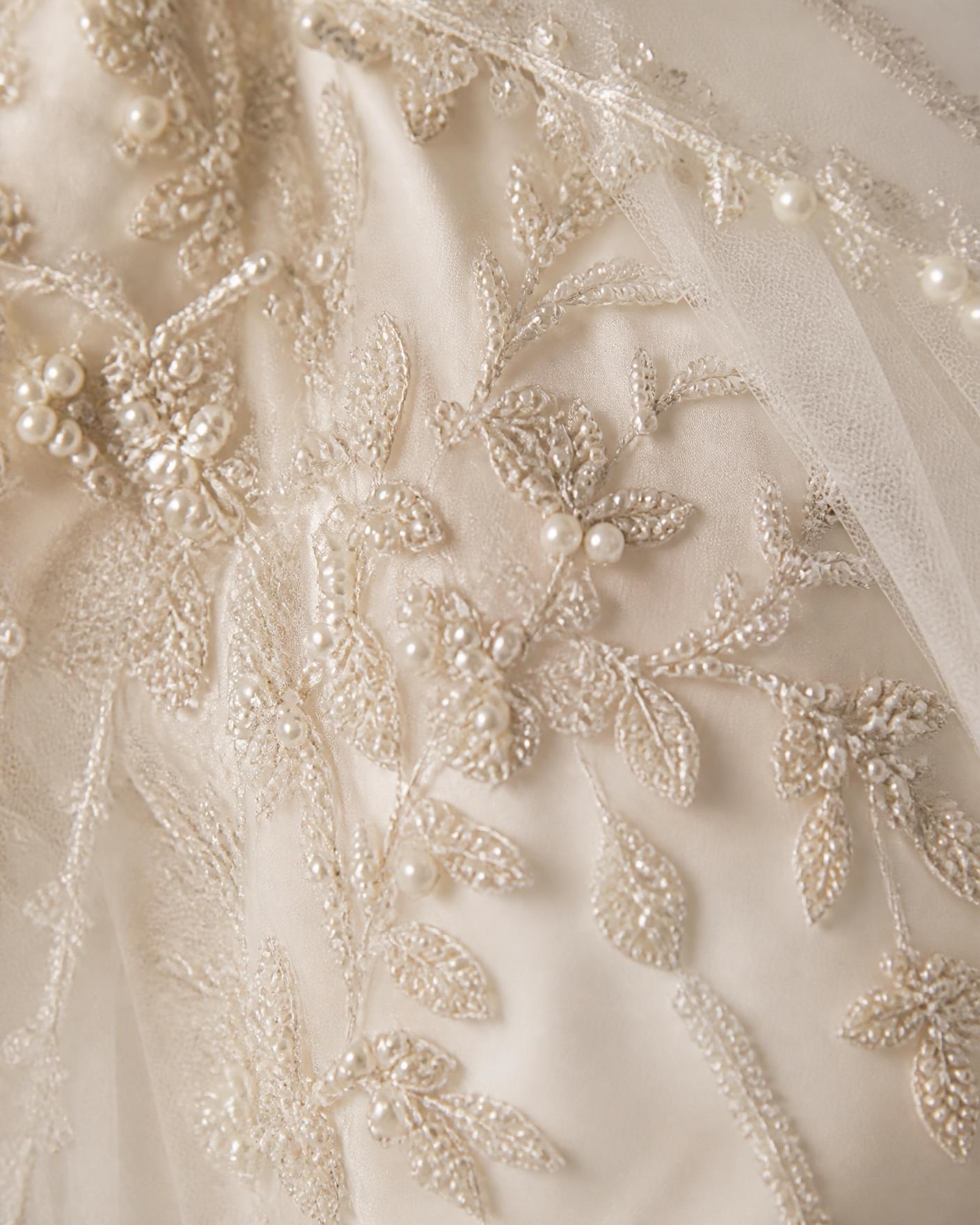 Close-up of hand-beaded pearl and crystal embroidery on ivory bridal tulle