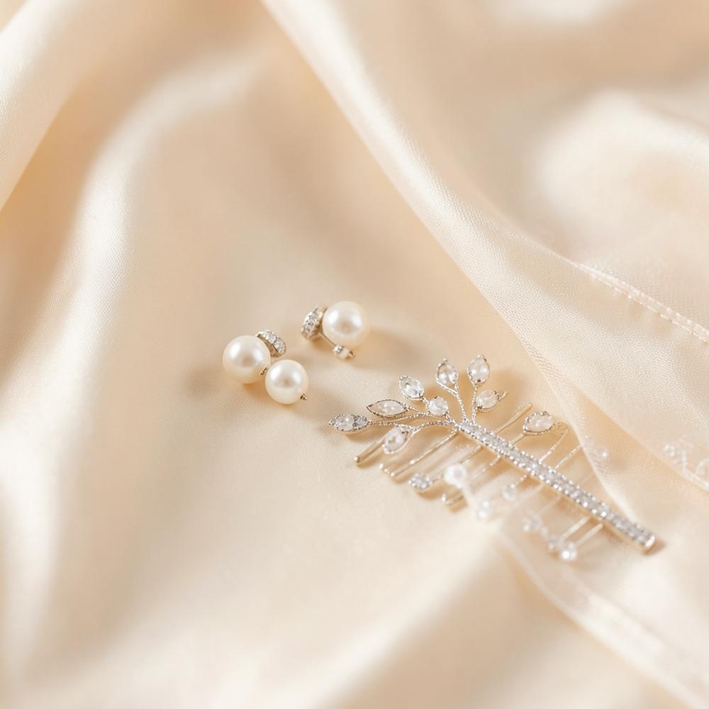 Pearl bridal earrings and a delicate veil comb resting on ivory silk